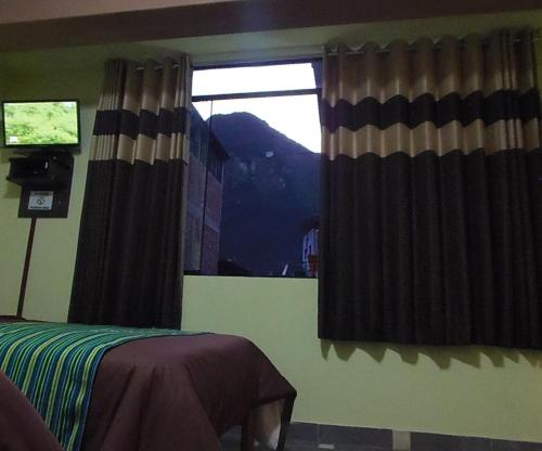 a bedroom with a window with curtains and a bed at Hostal Pablo's House in Machu Picchu