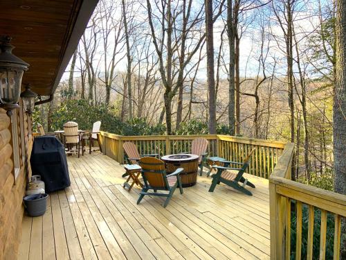 a wooden deck with chairs and tables and a grill at The Escape Cabin in Boone