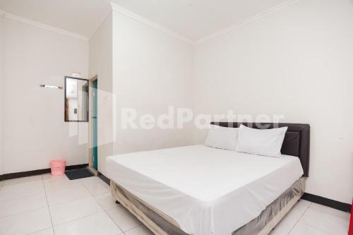 a bedroom with a white bed in a room at Wisma Juanda Bogor Mitra RedDoorz in Bogor