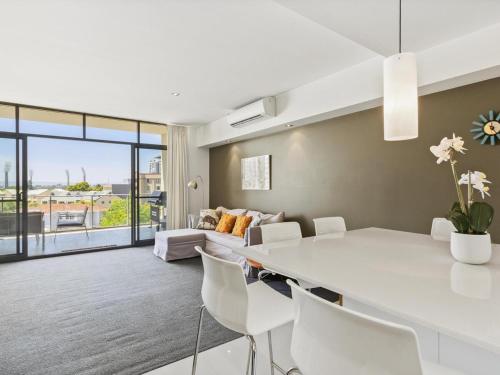 sala de estar con mesa blanca y sillas en 2bdrm Skyline Views - Prime for River, WACA, OPTUS Stadium en Perth