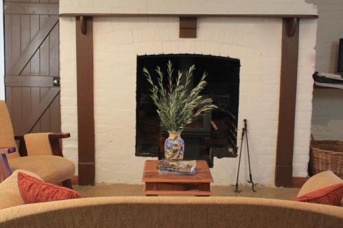 a living room with a fireplace with a vase on a table at Woolmers Estate in Longford