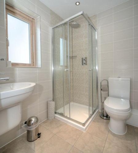a bathroom with a shower and a toilet and a sink at House 10 in Looe