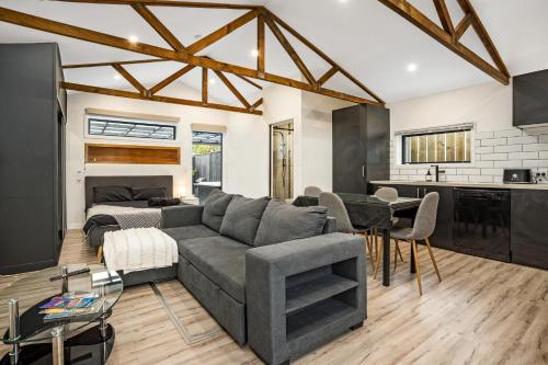 a living room with a gray couch and a kitchen at Studio Unit with Spa Bath in Christchurch