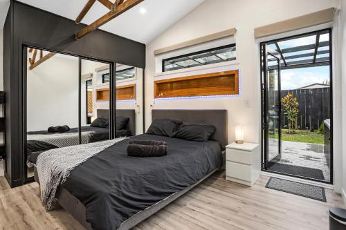 2 camas en un dormitorio con ventanas grandes en Studio Unit with Spa Bath en Christchurch
