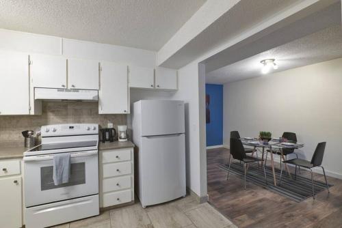a kitchen with a white refrigerator and a table with chairs at 2bedroom suite w/ great access into & out the city - 7818 in Calgary