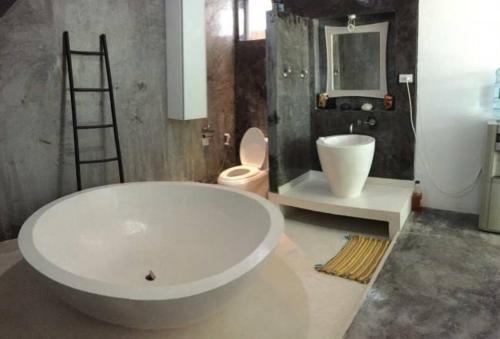 a bathroom with a large white tub and a toilet at La maison du bonheur à samui in Koh Samui