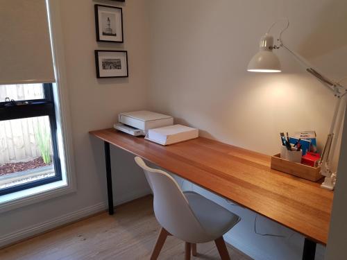 a desk with a chair next to a window and a lamp at NAUTILUS in Point Lonsdale