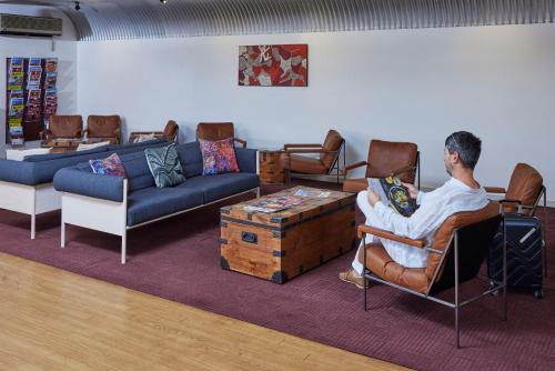 a man sitting in a chair in a living room at Outback Hotel in Ayers Rock