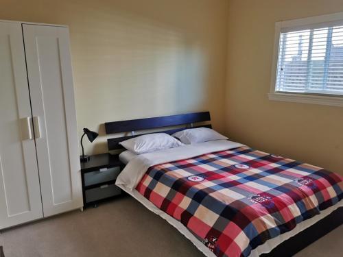 a bedroom with a bed with a checkered blanket at Nini Sweet home in Richmond