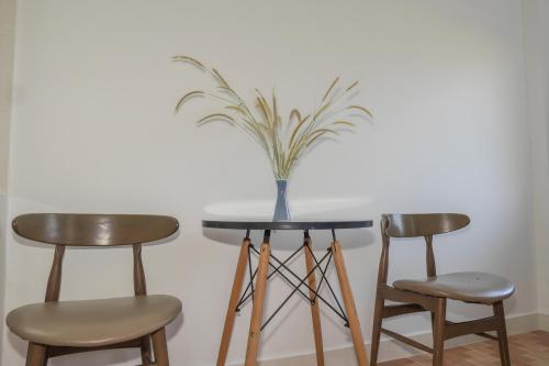 a table with two chairs and a vase with a plant on it at Nhà Nghỉ Vườn Oải Hương LAVENDER GARDEN GUEST HOUSE in Phu Quoc