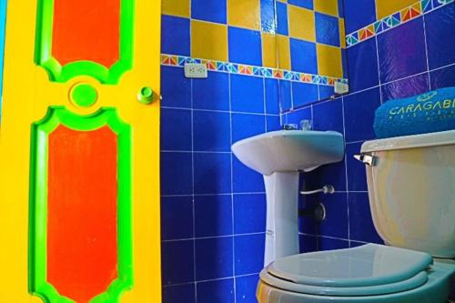 a bathroom with a toilet and a colorful wall at Chalet Villa Mar in Armenia