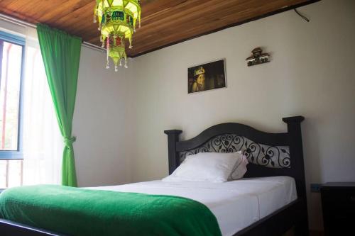 a bedroom with a bed with a green blanket and a chandelier at Chalet Villa Mar in Armenia
