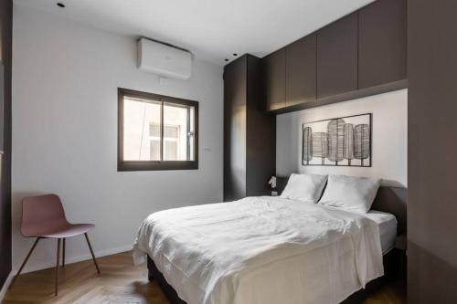 ein Schlafzimmer mit einem großen weißen Bett und einem Stuhl in der Unterkunft BnBennaim - Bella apartment in Tel Aviv