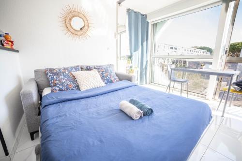 - un lit bleu dans une chambre avec une grande fenêtre dans l'établissement LA GRANDE MOTTE - PARKING - PLAGE - PORT -CENTRE VILLE, à La Grande Motte