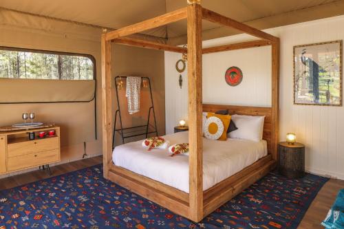 sypialnia z łóżkiem z baldachimem i niebieskim dywanem w obiekcie Two Fat Blokes African Safari Glamping w mieście Pokolbin