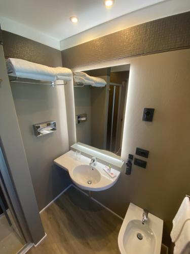 a bathroom with a sink and a mirror and a toilet at Green Park Hotel in Peschiera del Garda