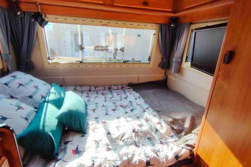 Bett auf der Rückseite eines Zimmers mit Fenster in der Unterkunft Camping-car vintage in Venette