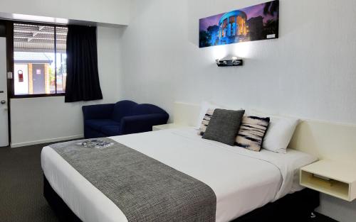 a hotel room with a bed and a blue chair at Archer Park Motel in Rockhampton