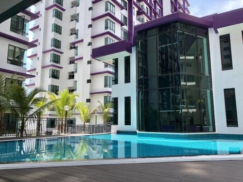 a hotel with a swimming pool in front of a building at Cozy Condo at Melaka Top Hill, 7-9pax in Ayer Keroh