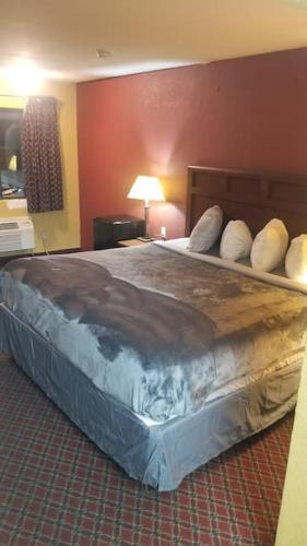 a large bed with pillows on it in a room at OSU 2 Queens Hotel Room 107 Hot Tub Booking in Stillwater