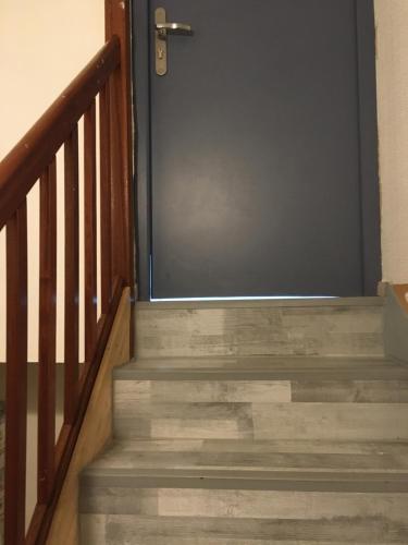 una puerta que conduce a una escalera con escalones de madera en Studio chez Virginie et Henri, en Le Mée-sur-Seine