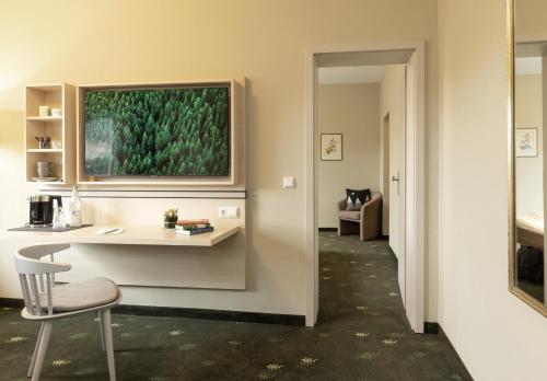 a room with a desk with a chair and a painting on the wall at Das Hohenried in Freudenstadt