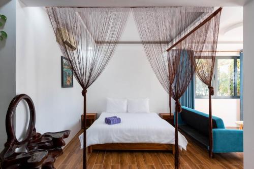フーコックにあるCoastal Village Phu Quocのベッドルーム(天蓋付きベッド1台、青いソファ付)