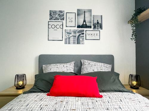 a bed with a red pillow and pictures on the wall at Red Lounge in Toulouse