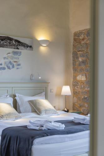 a bedroom with two beds and a stone wall at Castello Antico Hotel in Gythio
