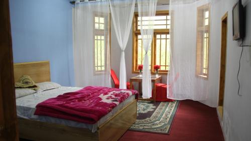 1 dormitorio con cama, mesa y ventanas en Rakaposhi Amin Hotel & Restaurant Pissan Hunza Nagar Gilgit Baltistan en Gilgit