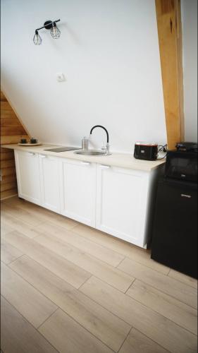 a white kitchen with a sink and a stove at Cabanele A Frame, Salciua Noua in Sălciua Nouă