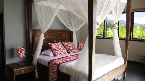 a bedroom with a canopy bed with red and white pillows at The Kubu Authentic Quite Place with Nice View in Silebeng