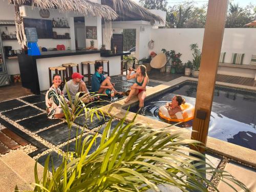 a group of people sitting around a swimming pool at Punta Kai Hotel & Hostal in Puerto Escondido