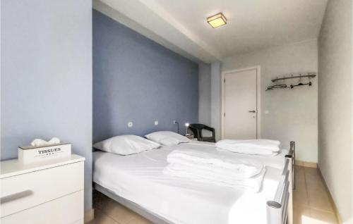 a bedroom with a white bed and a blue wall at Nice Apartment In Bredene With Kitchen in Bredene