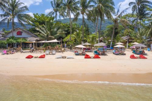 a beach with chairs and umbrellas and palm trees at Coco Sunset Beach in Ban Bang Po
