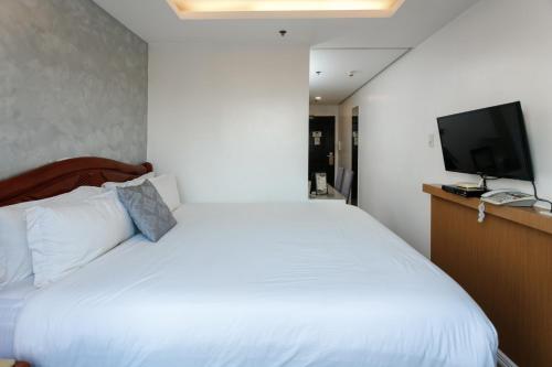 a bedroom with a white bed and a flat screen tv at Regency Grand Suites in Manila