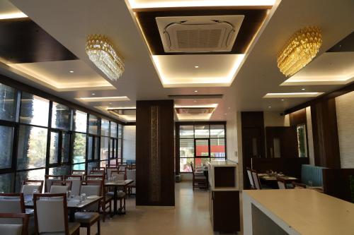 a dining room with tables and chairs and windows at Blisss Hotel Kolhapur in Kolhapur