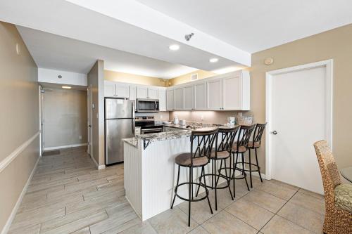 eine Küche mit weißen Schränken und Barhockern in der Unterkunft Shoalwater 804 in Orange Beach