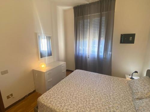 莫尼加的住宿－Appartamento San Michele，一间卧室配有一张床、一个梳妆台和一扇窗户。