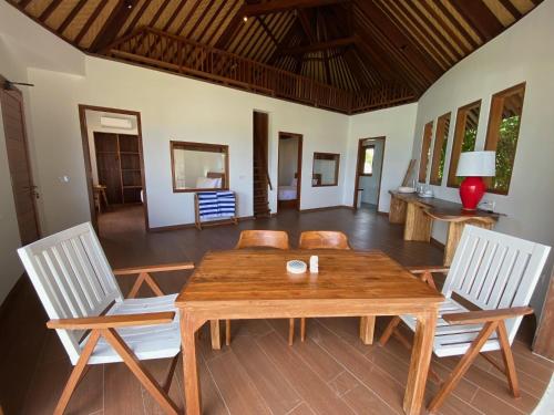 a dining room with a wooden table and two chairs at Bombora Balangan Resort in Ungasan