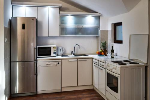 a kitchen with white cabinets and a stainless steel refrigerator at Family Residence Petrovac in Petrovac na Moru