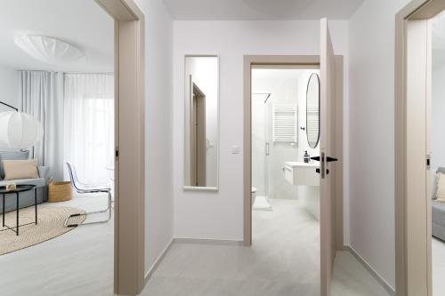 a white bathroom with a sink and a mirror at Apartamenty Lambert Grzybowo in Grzybowo