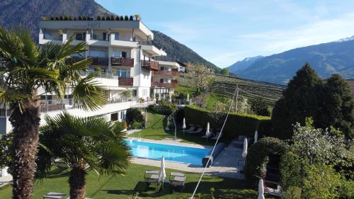 un hotel con piscina e montagne sullo sfondo di Hotel Garni Herz a Tirolo