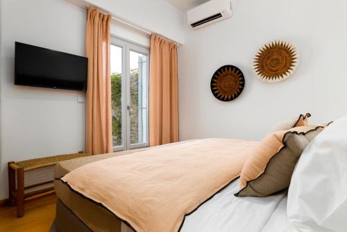 a bedroom with a bed and a tv and a window at Mirabilia, Unique view meets true elegance in Krotiri