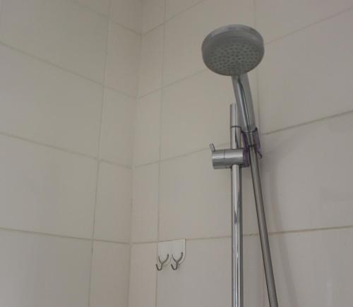 a shower head in a bathroom with white tiles at Abigail's Studio Apartment @ Trift Tower in Windhoek