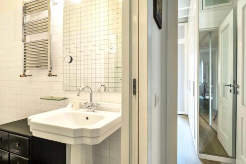 uma casa de banho branca com um lavatório e um espelho em Lovely apartment on the Navigli river by Easylife em Milão