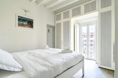 um quarto branco com uma cama branca e uma janela em Lovely apartment on the Navigli river by Easylife em Milão