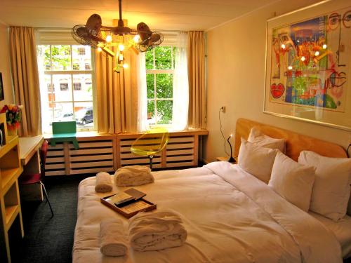 ein Schlafzimmer mit einem weißen Bett mit einem Buch darauf in der Unterkunft Rosalia's Menagerie Cocktail bar & InnUpstairs in Amsterdam