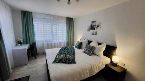 a bedroom with a bed with a desk and a window at 4Rooms Central-Modern near MTU with Balcony, The Beach by Lakescape FeWos in Friedrichshafen