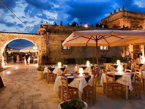 un ristorante con tavoli e ombrelloni in un cortile di La Casa sulla Spiaggia a Marzamemi